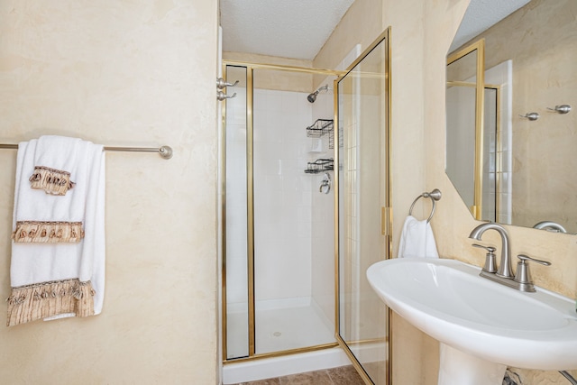 full bath with a sink, a shower stall, and a textured ceiling