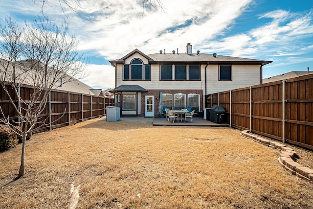 back of house featuring a fenced backyard, a chimney, a yard, central air condition unit, and brick siding