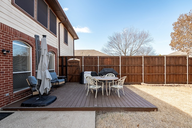 deck with outdoor dining area, fence, and a grill