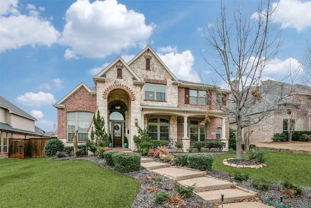 view of front of home with brick siding, fence, and a front yard