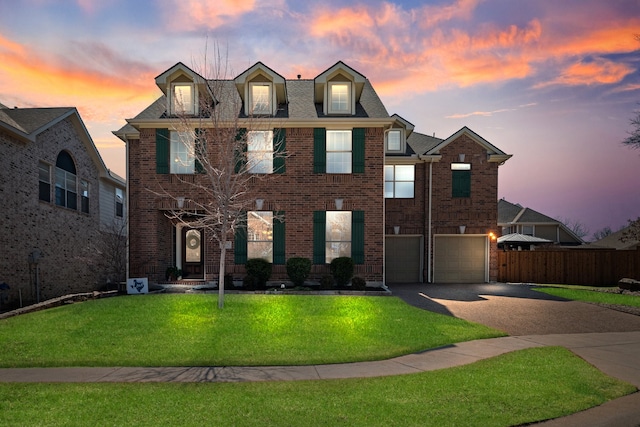 view of front of property featuring concrete driveway, an attached garage, fence, a yard, and brick siding