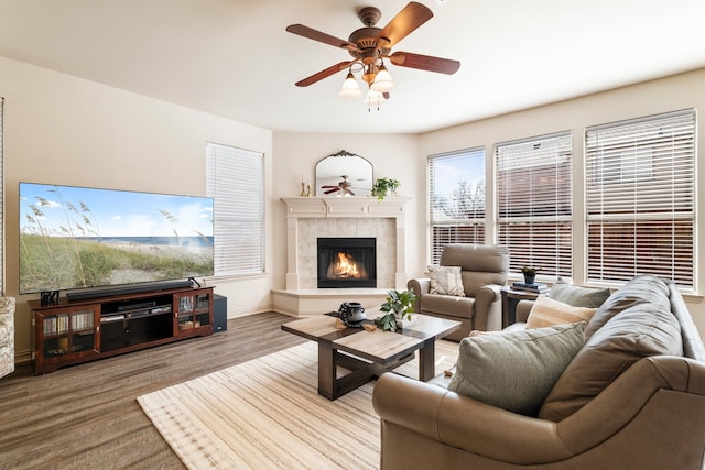 living room with baseboards, a ceiling fan, wood finished floors, and a tile fireplace