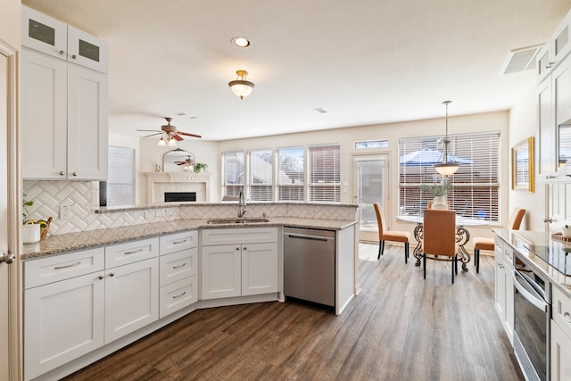 kitchen featuring stainless steel appliances, backsplash, dark wood-type flooring, white cabinets, and a sink