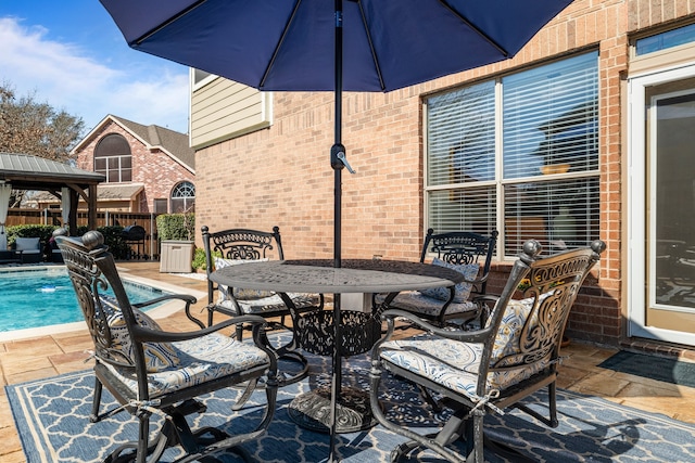 view of patio featuring a fenced in pool, outdoor dining area, fence, and a gazebo