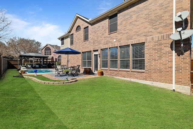 back of property with brick siding, a patio, a gazebo, and fence