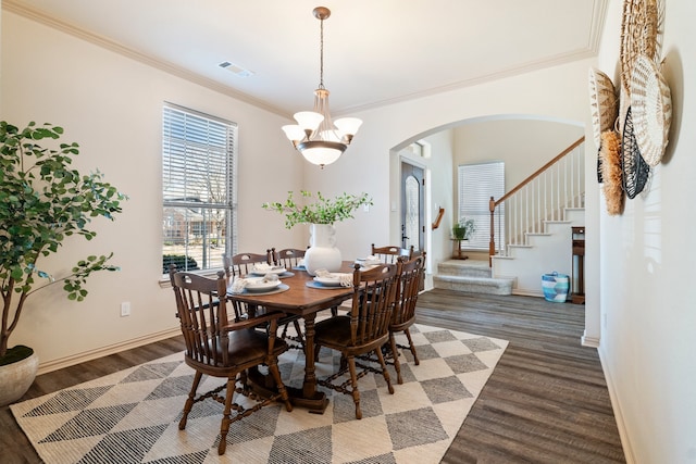 dining space with arched walkways, dark wood-type flooring, visible vents, and a notable chandelier