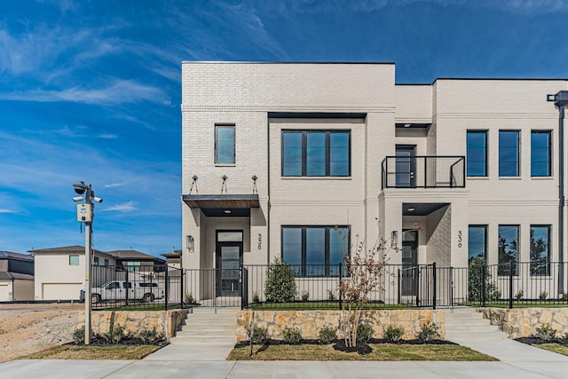 townhome / multi-family property featuring a fenced front yard and brick siding