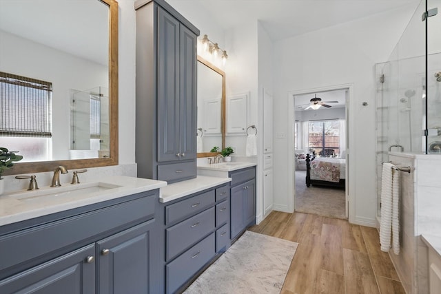 ensuite bathroom with wood finished floors, ceiling fan, vanity, a shower stall, and ensuite bath