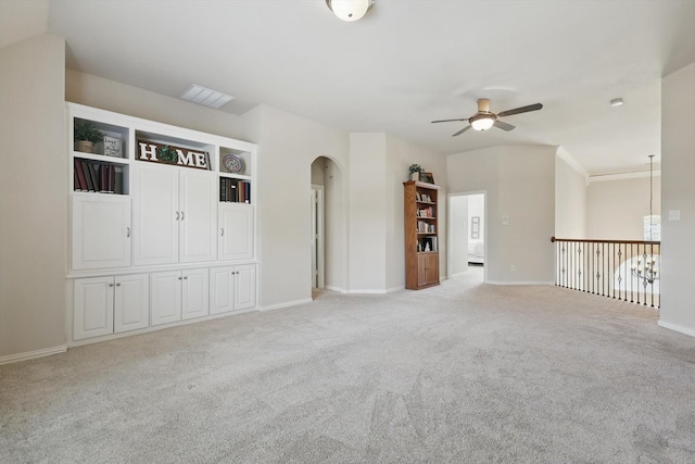 spare room with light carpet, baseboards, arched walkways, and ceiling fan