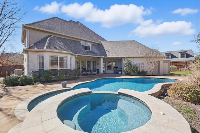 view of swimming pool featuring a pool with connected hot tub, a patio, and fence