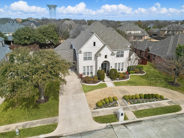 view of front of home with driveway, stone siding, a residential view, roof with shingles, and a front yard