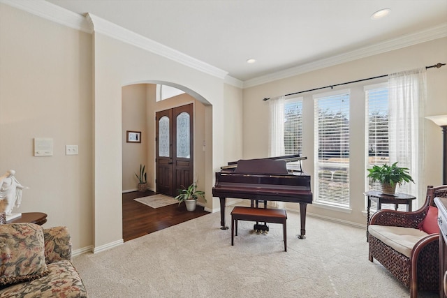 carpeted foyer with arched walkways, recessed lighting, baseboards, and crown molding