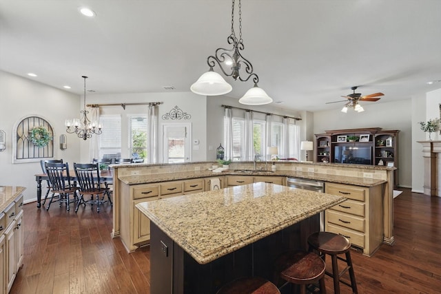 kitchen with a breakfast bar area, a spacious island, open floor plan, light stone countertops, and decorative light fixtures