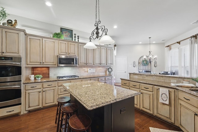 kitchen featuring pendant lighting, decorative backsplash, appliances with stainless steel finishes, a kitchen island, and a kitchen breakfast bar