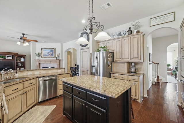 kitchen with appliances with stainless steel finishes, a center island, a sink, and light stone countertops