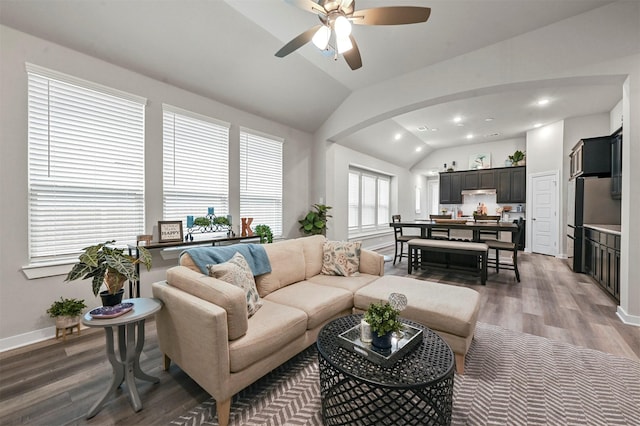 living room with arched walkways, lofted ceiling, recessed lighting, dark wood-type flooring, and baseboards