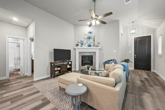 living area featuring a tile fireplace, wood finished floors, visible vents, and baseboards