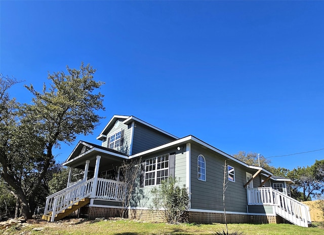 view of front facade with a porch, a front yard, and stairway