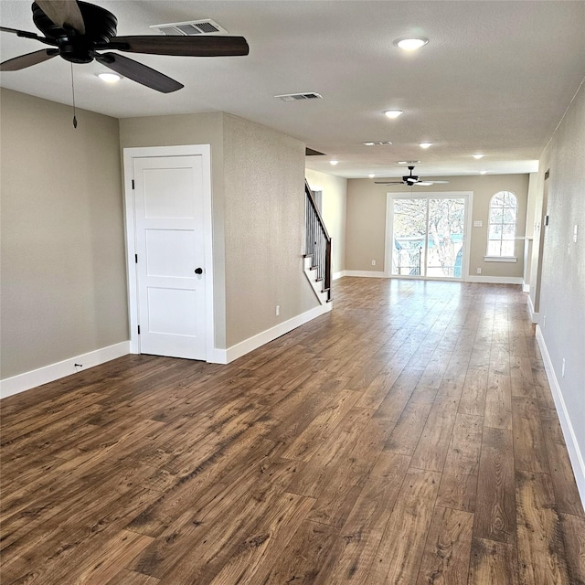 spare room featuring dark wood-style flooring, visible vents, stairway, and baseboards