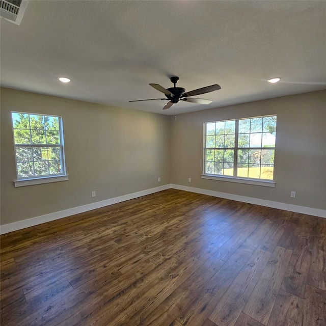 spare room with plenty of natural light, dark wood finished floors, and baseboards