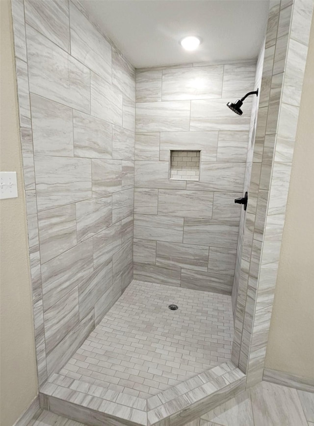 bathroom with tiled shower and baseboards