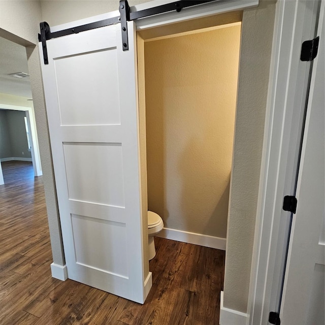 bathroom with baseboards, a textured wall, toilet, and wood finished floors