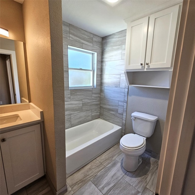 bathroom with bathtub / shower combination, a textured wall, vanity, and toilet