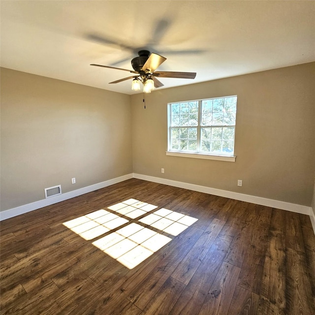 empty room with dark wood-style floors, visible vents, baseboards, and a ceiling fan