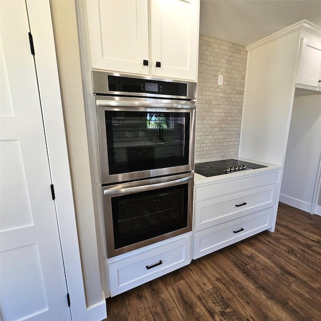 kitchen with tasteful backsplash, white cabinets, dark wood finished floors, black electric stovetop, and double oven