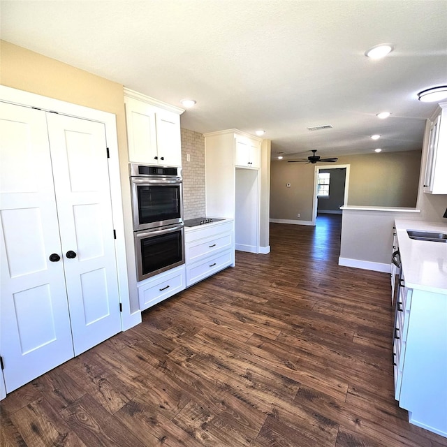 kitchen with visible vents, dark wood-type flooring, black electric stovetop, stainless steel double oven, and white cabinetry