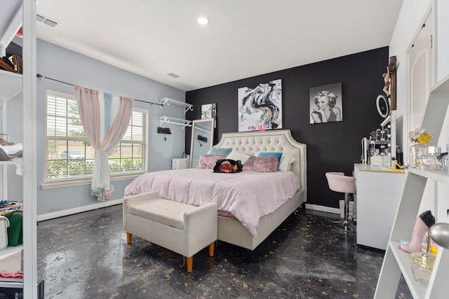 bedroom with baseboards, an accent wall, and finished concrete floors