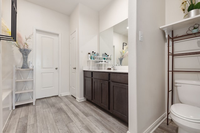 full bathroom with toilet, a closet, wood finished floors, and vanity