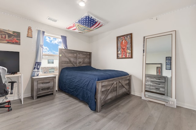 bedroom with light wood-type flooring, visible vents, and baseboards