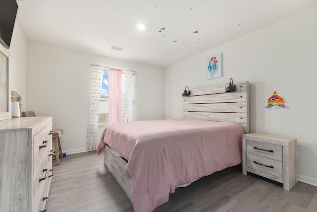 bedroom with baseboards, visible vents, and light wood finished floors