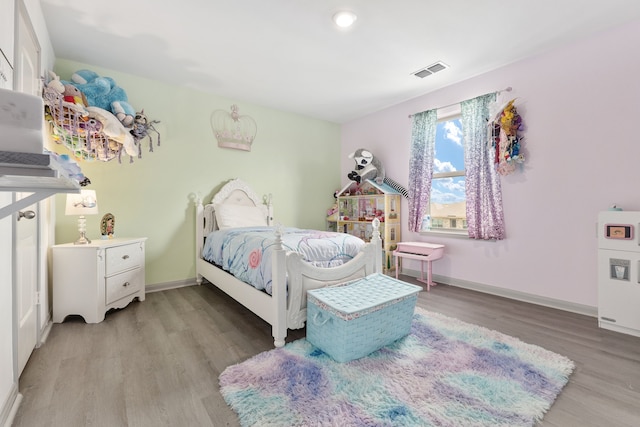 bedroom with visible vents, baseboards, and wood finished floors