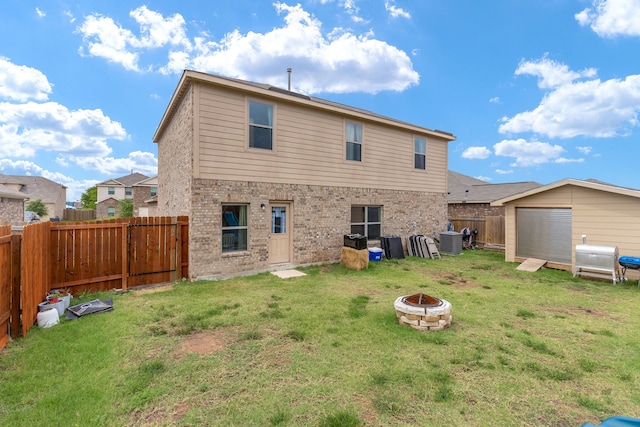 back of property featuring brick siding, a yard, central air condition unit, an outdoor fire pit, and a fenced backyard