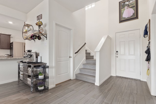 foyer featuring light wood-style floors, baseboards, and stairs