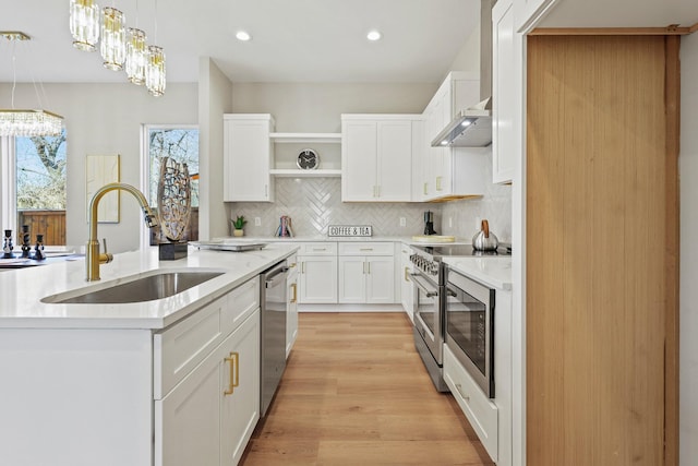 kitchen featuring appliances with stainless steel finishes, white cabinets, light countertops, and a sink