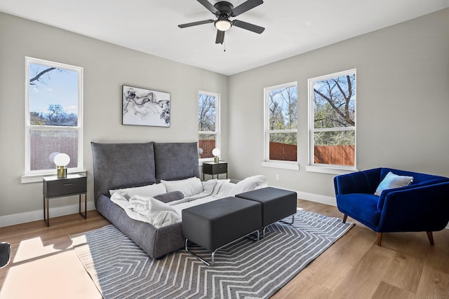 living room with wood finished floors, a ceiling fan, and baseboards