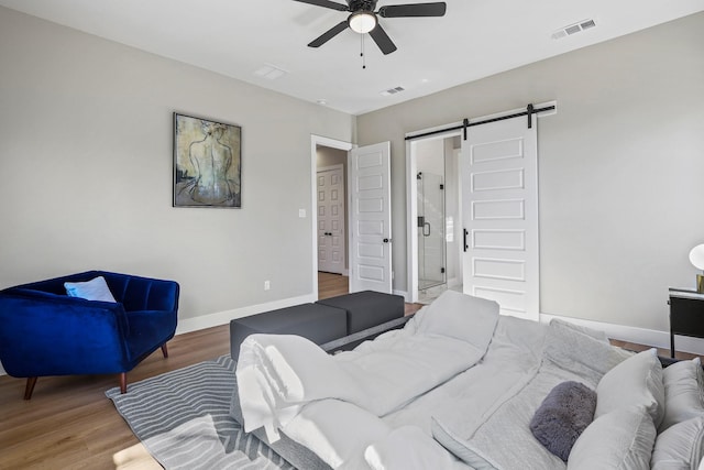 bedroom featuring wood finished floors, visible vents, baseboards, and a barn door