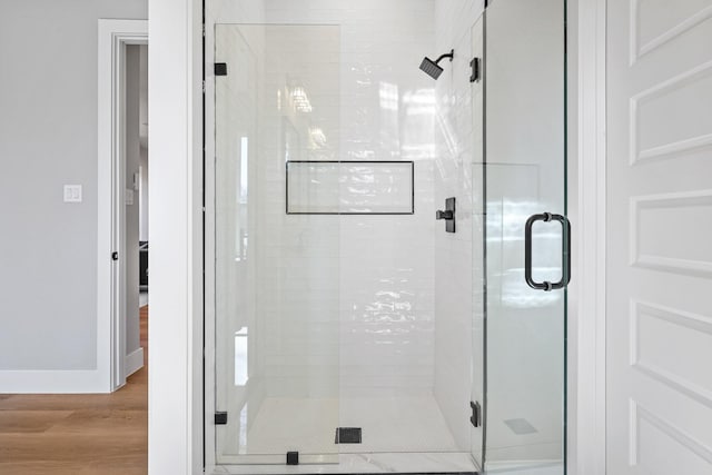 bathroom featuring a stall shower, baseboards, and wood finished floors