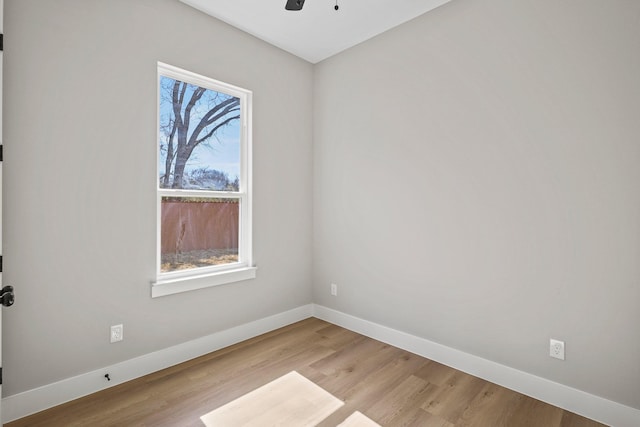 empty room with baseboards, ceiling fan, and light wood-style floors