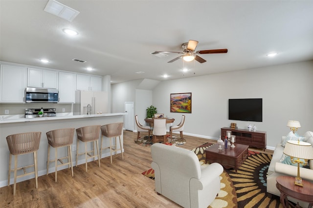 living room with light wood-type flooring, visible vents, and recessed lighting