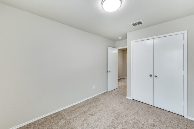 unfurnished bedroom featuring light carpet, baseboards, visible vents, and a closet