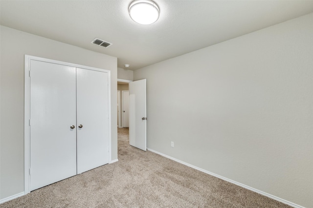 unfurnished bedroom featuring light carpet, baseboards, visible vents, and a closet