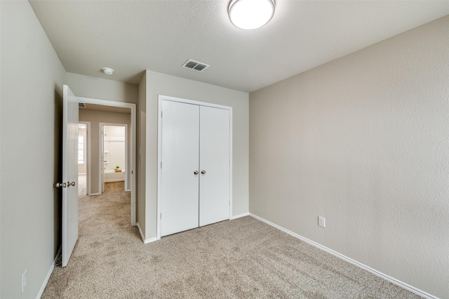 unfurnished bedroom featuring light carpet, baseboards, visible vents, and a closet