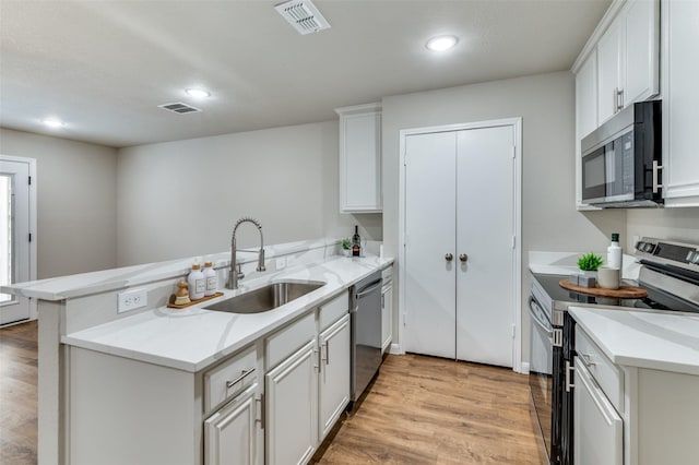 kitchen featuring stainless steel appliances, a peninsula, visible vents, and white cabinetry