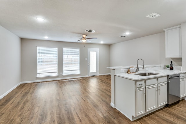 kitchen featuring visible vents, stainless steel dishwasher, open floor plan, white cabinets, and a sink