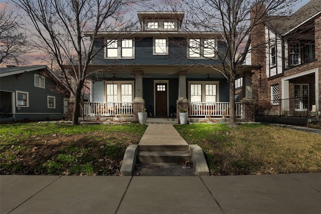 american foursquare style home with covered porch, brick siding, and a front lawn