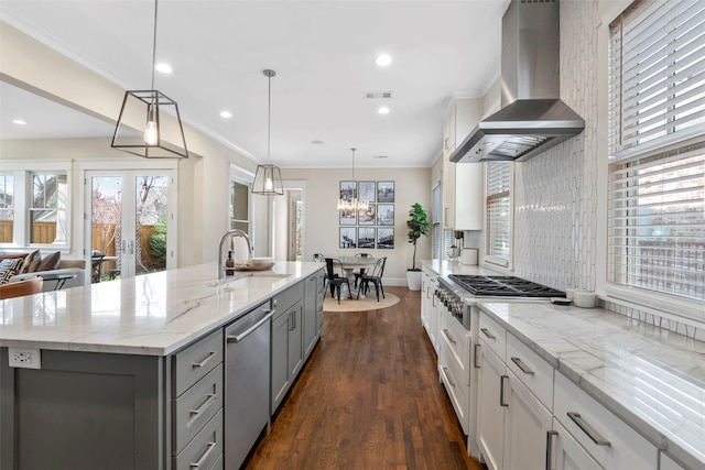 kitchen featuring decorative light fixtures, a large island, appliances with stainless steel finishes, a sink, and wall chimney exhaust hood